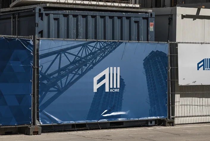 ACME hoarding around a site: the mark over a crane and a tower in blue