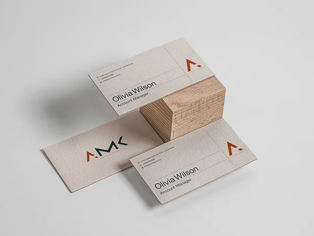 AMK business cards in sand with the terracotta symbol, around a timber block