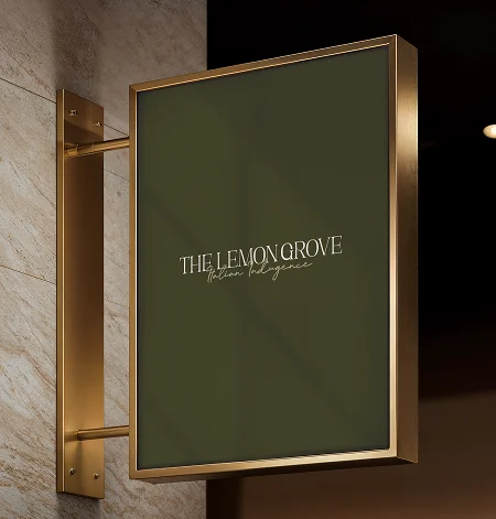 A brass-framed Lemon Grove hanging sign on a marble wall