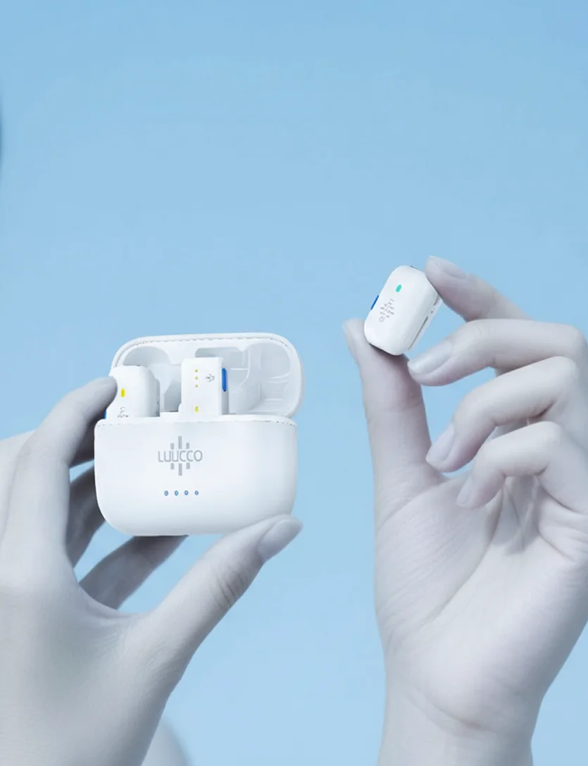 A LUUCCO wireless microphone case held open in one hand, a microphone held up in the other, on sky blue