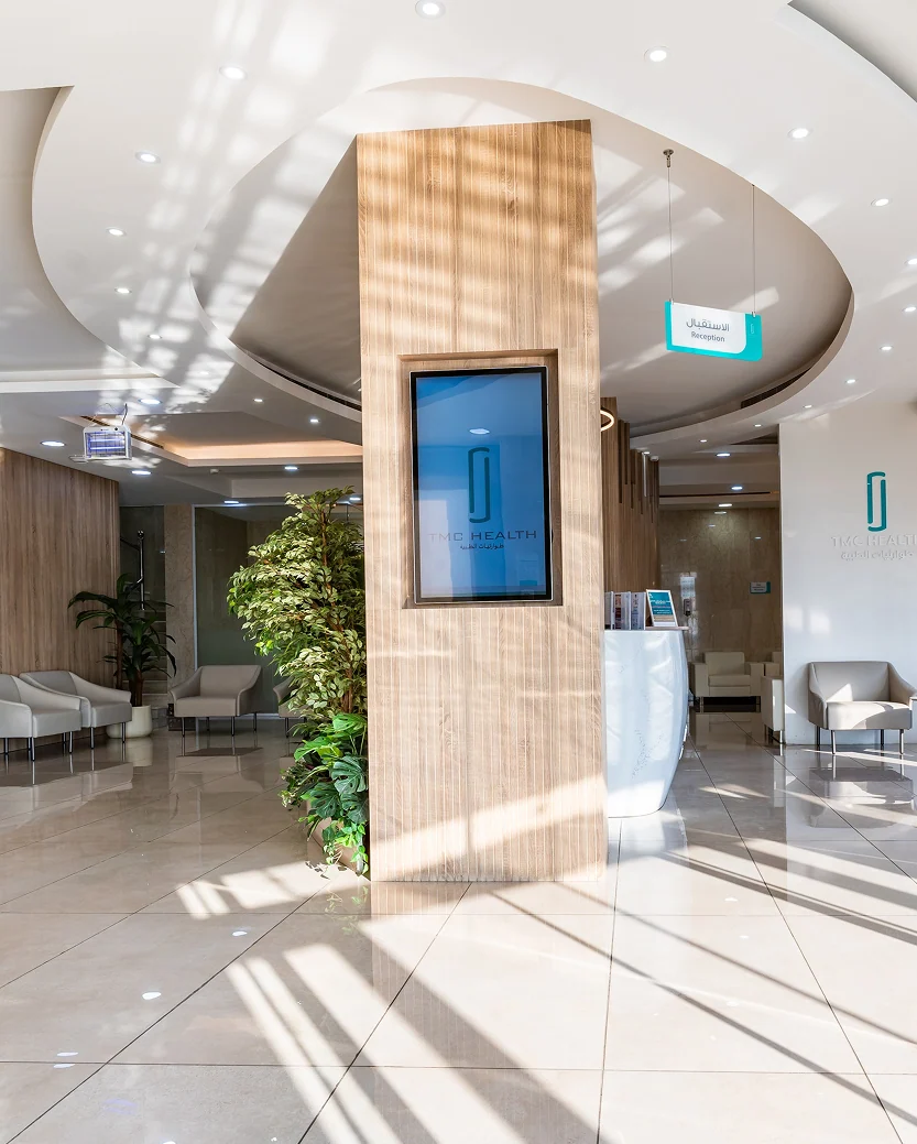 The entrance lobby of the TMC Health Jubail Medical Center, the teal mark on its screens and signage